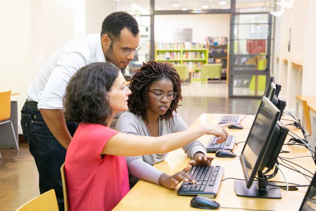 What is ICAS? Three people positioned around a computer helping to complete a project together discussing ICAS