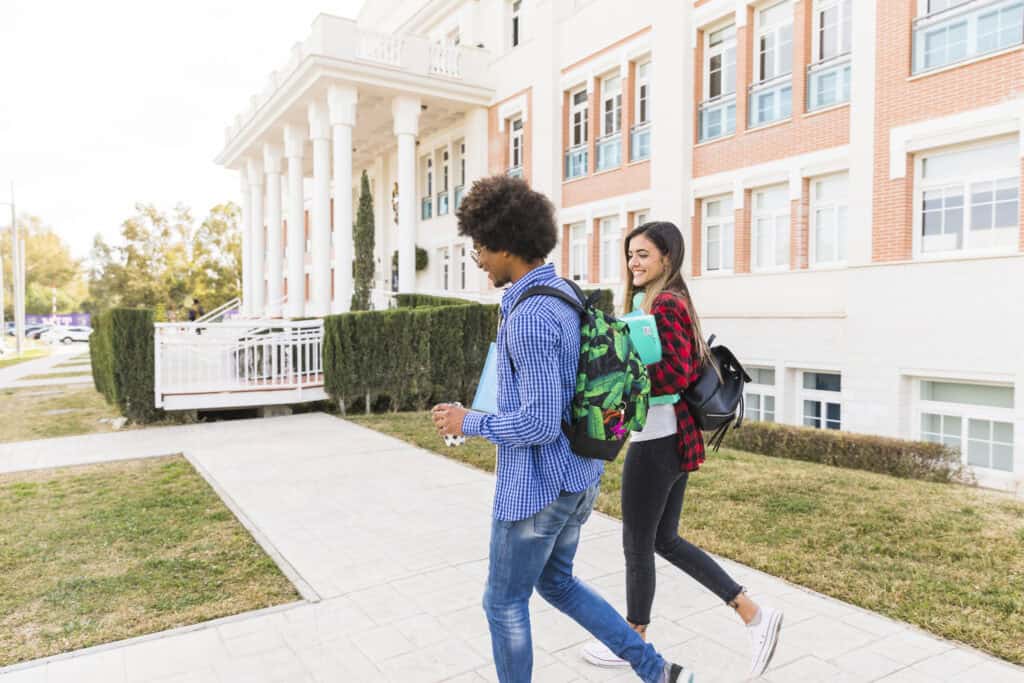 Two students walk together outside a university building.