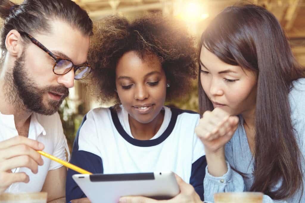 A team of students work together on a school project on an iPad.