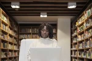 A student studying digital maturity on her laptop in a library.