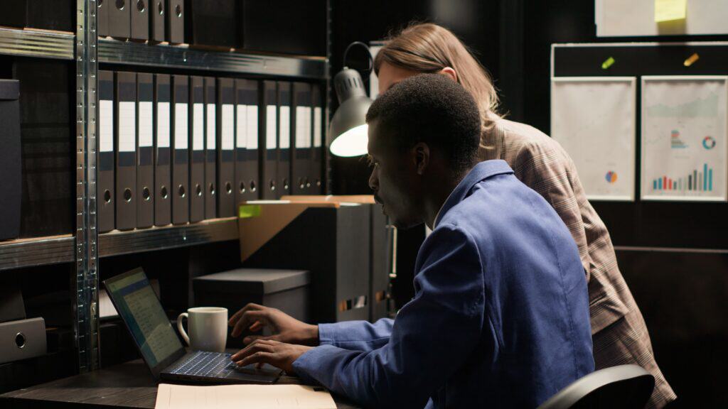 Two workers at a higher education institution analyse their data integrity on a laptop